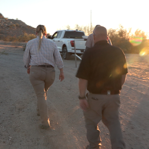 Woman walking on dirt path toward work truck.
